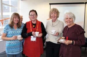 Four smiling women holding cups of tea