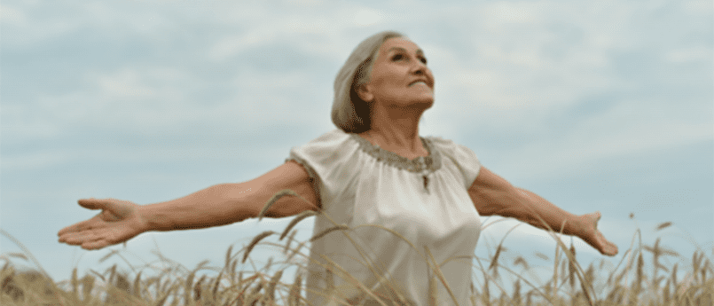 woman standing in field with open arms