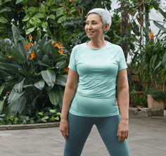 Active middle aged woman in a light blue tshirt and teal pants, ready to exercise.