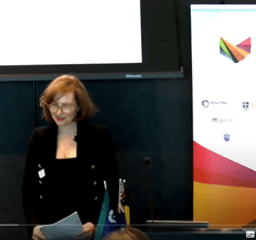 Gabrielle Jackson standing in front of an audience with a VCCC Alliance banner behind her.