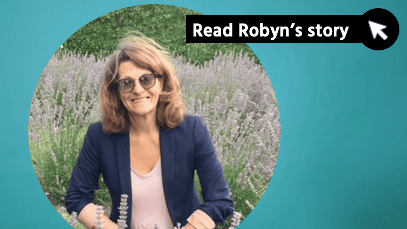 Read Robyn's story. Photo of Robyn out in nature, with flowering plants  in the background.
