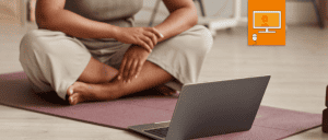 woman sitting on a mat in front of laptop.