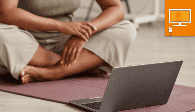 woman sitting on a mat in front of laptop.