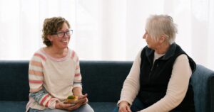 Two women sitting on a couch chatting