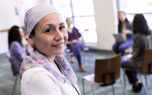 woman in headscarf in foreground with chairs and a group of people sitting in the background.